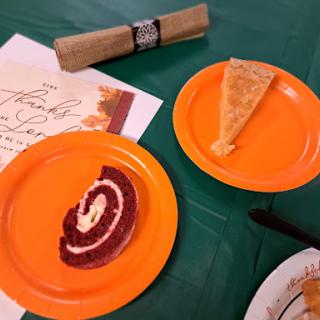 A festive spread featuring red velvet cake and pumpkin pie on vibrant orange plates.
