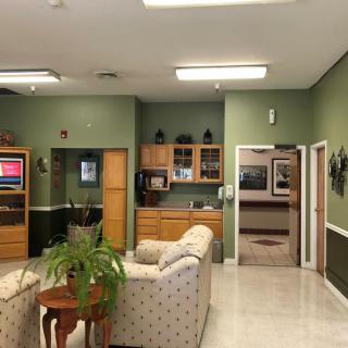 A cozy waiting room with sofas, a kitchenette, and a television.