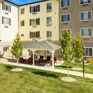 A sunny day view of a residential building with a gazebo and well-maintained lawn.