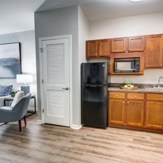 Modern apartment kitchen with adjacent living area and wooden cabinetry.