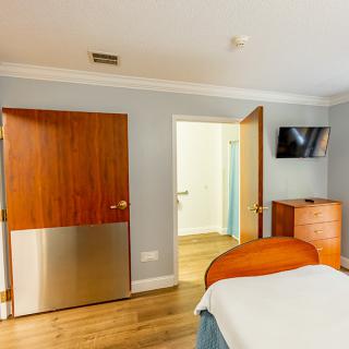 A modern bedroom with wooden furnishings and a wall-mounted TV.