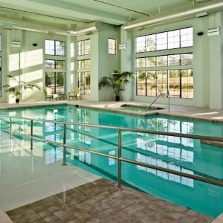 A sunlit indoor swimming pool surrounded by large windows and modern architecture.