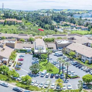 Aerial view of a suburban area with buildings surrounded by greenery and a parking lot.