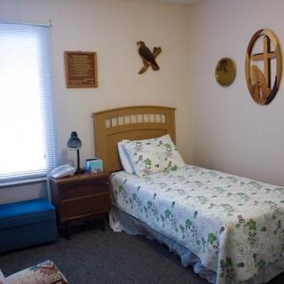 A small bedroom with a single bed, nightstand, and various wall decorations.