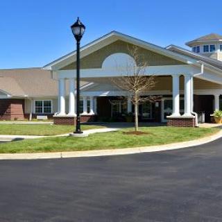 A modern building entrance with landscaping and a clear sky.