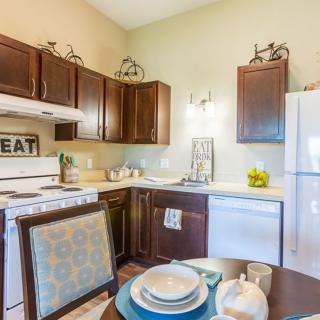 A cozy kitchen with dark wood cabinets, a dining table set for a meal, and various kitchen appliances.