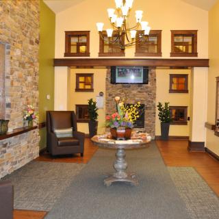 A cozy lobby area featuring a stone wall, chandelier lighting, and a central decorative table with floral arrangements.