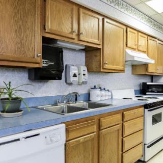 A cozy kitchen featuring wooden cabinets and blue countertops, complete with essential appliances.