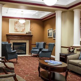 A cozy lobby interior featuring a fireplace, comfortable seating, and elegant columns.