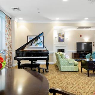 A elegantly furnished living room featuring a grand piano, comfortable seating, a large television, and tasteful artwork.