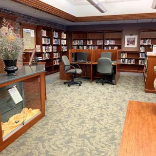 A quiet library space with bookshelves, chairs, and tables for reading.