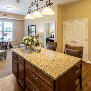 A cozy kitchen space featuring a granite island, wooden seating, and warm lighting.
