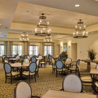 Elegantly designed dining room with round tables and chandelier lighting.