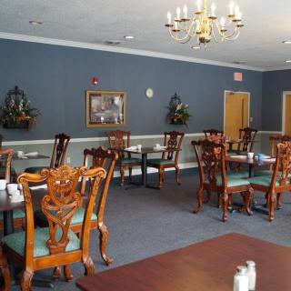 An elegant dining room with wooden tables and chairs, adorned with a chandelier and blue walls.