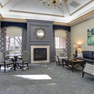 A cozy living room with elegant furnishings and a central fireplace.