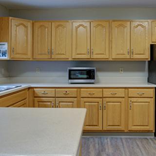 A kitchen featuring wooden cabinets and a countertop with a microwave.