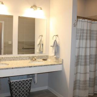 A modern bathroom with a double sink vanity, large mirrors, and a shower area with a striped curtain.