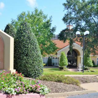 A scenic view of a well-maintained garden with lush greenery and a beautifully designed building in the background.