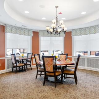 A cozy dining area with a chandelier and multiple tables surrounded by chairs.