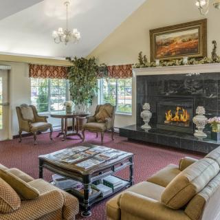 A cozy living room with elegant furnishings, centered around a fireplace and decorated with a painting above the mantel.