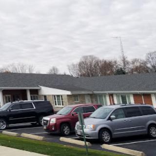 A view of a motel with several parked cars under a cloudy sky.