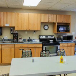 A break room kitchen with various appliances and a table with chairs.