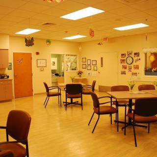 A brightly lit community center or waiting room with several tables and chairs arranged neatly.