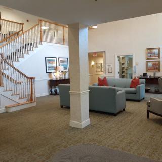 A cozy lobby area featuring sofas, a staircase, and tasteful decor.