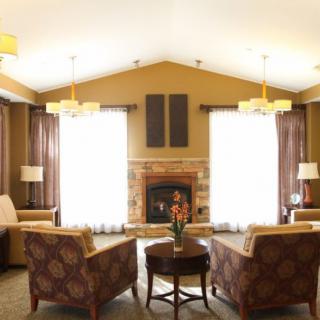 A cozy living room with a fireplace, armchairs, and elegant lighting.