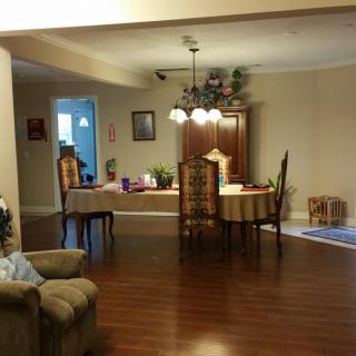 A cozy dining room with a wooden table and chairs, a chandelier, and hardwood flooring.