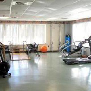 A well-lit gym with various fitness equipment including treadmills, exercise bikes, and an exercise ball.