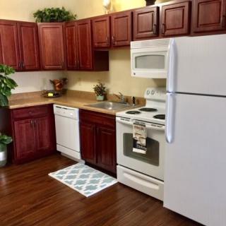 A modern kitchen with wooden cabinets, white appliances, and hardwood floors.