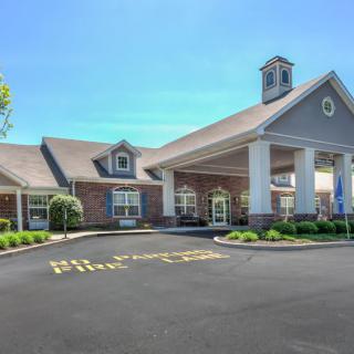 A building with a grand entrance and well-maintained landscaping under a clear blue sky.