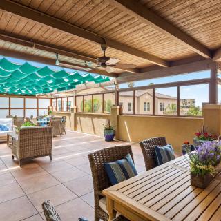 A cozy outdoor patio with a wooden table and comfortable seating, featuring a sunshade for a relaxing ambiance.