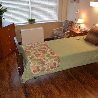 A neatly arranged bedroom with a single bed, bedside table, and a lamp.