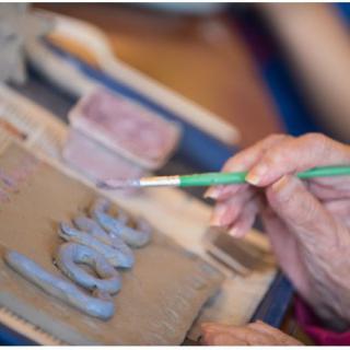 A person painting letters on a clay surface with a brush.