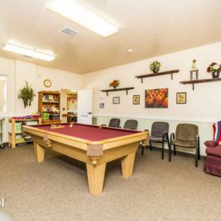 A cozy game room featuring a pool table, seating area, and decorative wall shelves.