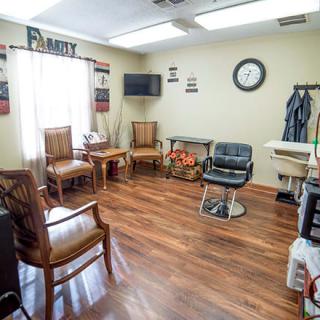 A cozy hair salon waiting area with wooden floors and a variety of chairs.