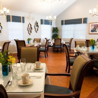 A well-lit dining room with neatly arranged tables and chairs, complemented by elegant decor.