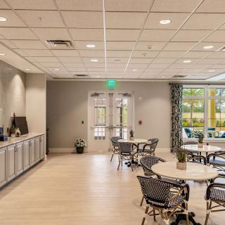 A modern indoor dining and meeting space with tables, chairs, and large windows allowing natural light.