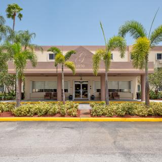 A hotel building with a landscaped entrance featuring palm trees.