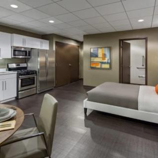 A modern studio apartment with a kitchen, dining area, and bedroom space.