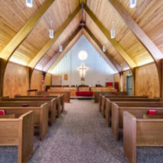 Interior view of a church featuring wooden pews and a prominent cross on the altar.