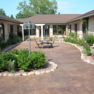 A peaceful courtyard featuring a patio with outdoor seating, surrounded by landscaped gardens.
