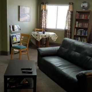 A cozy living room with a sofa, coffee table, and a small dining area by the window.