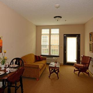 A cozy living room with a brown couch and matching chairs, featuring a table and large window.
