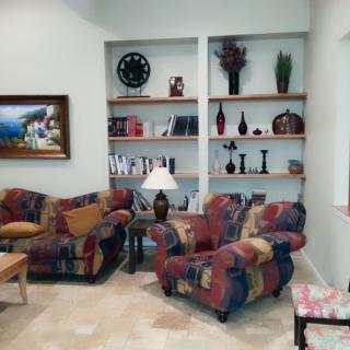 A cozy living room with colorful furniture and decorative shelves.
