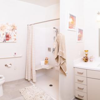 A bright and clean bathroom with modern decor, featuring a shower, vanity, and wall artwork.