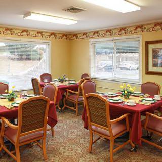 A cozy dining room with neatly arranged tables and chairs, featuring a warm interior design.
