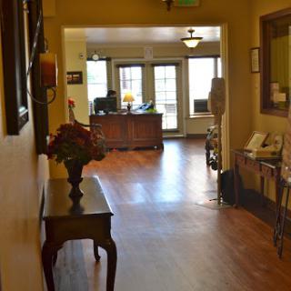 A welcoming hallway leading to a reception area with warm lighting and wooden floors.